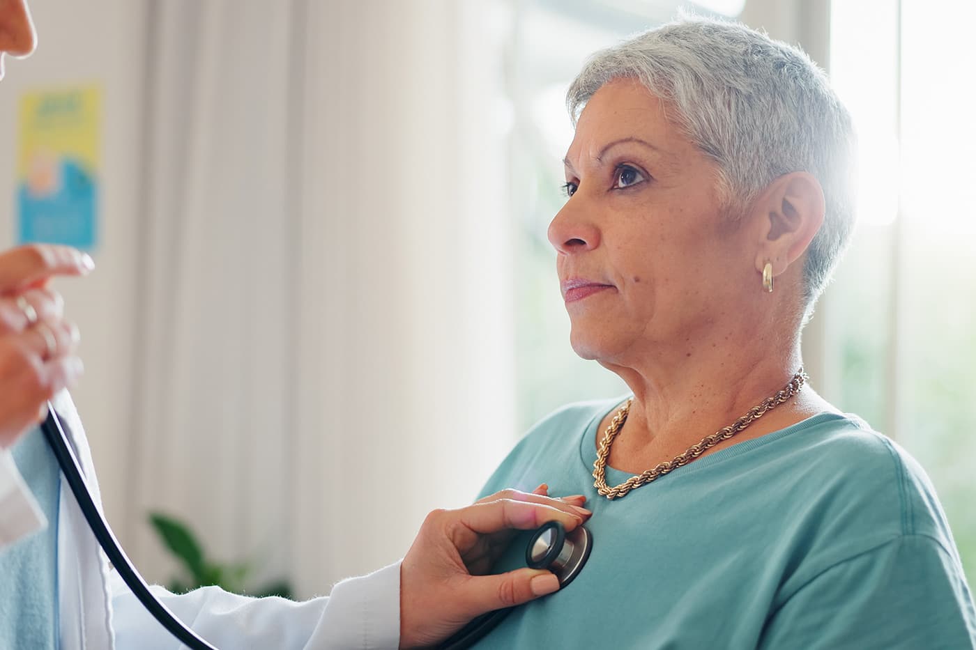 A doctor uses a stethoscope to examine an older woman during a medical appointment.